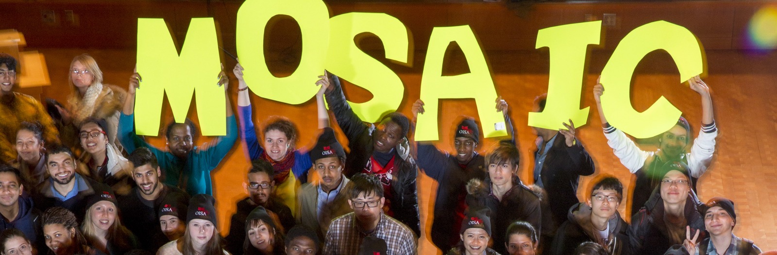 large group of students holding a signs that spell out MOSAIC