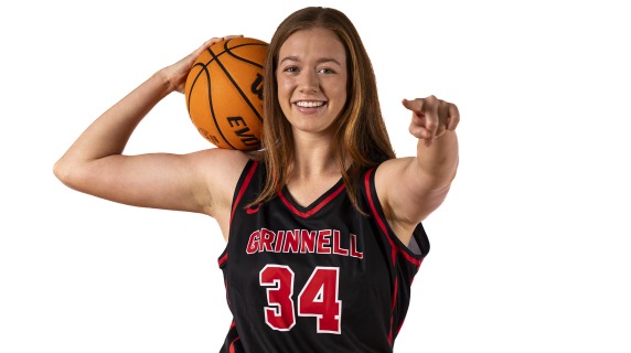 Smiling, Sara holds a basketball and points at the camera