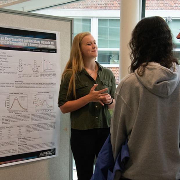 student presents research poster to faculty