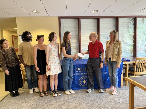 Students giving check to adults in office