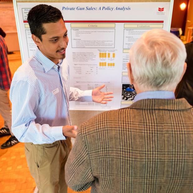 student presents research poster to faculty