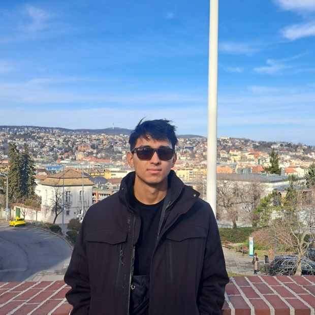 Sauryanshu stands in front of a vast city landscape, looking at the viewer