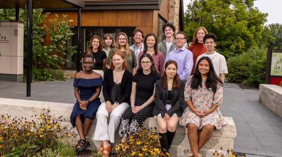 Grinnell's senior interviewer student workers smile for a group photo in front of a modern admission building