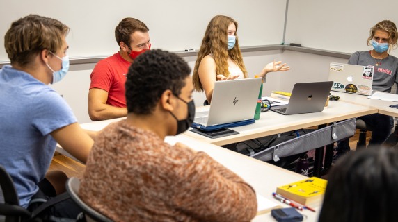 Students sit around a table in a classroom discussion