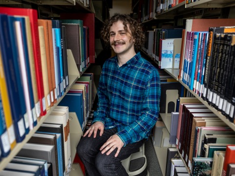 Daniel Rosenbloom pulls a book from the library shelf.