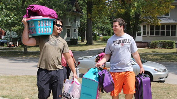 A parent helps a student carry luggage.