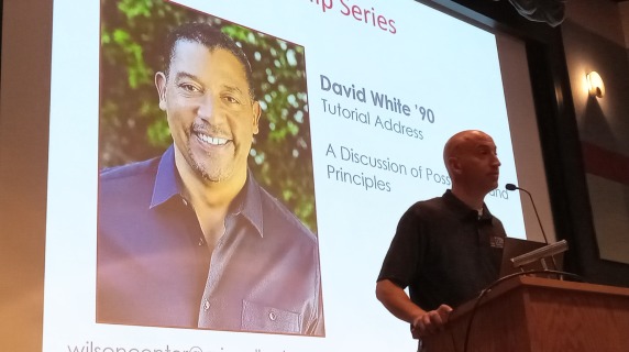 Man at a podium introduces a guest speaker.