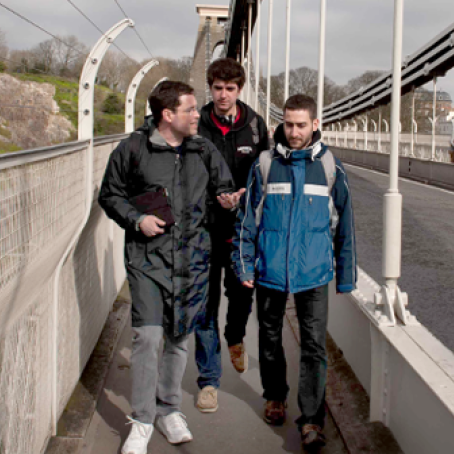 Three students on bridge walkway