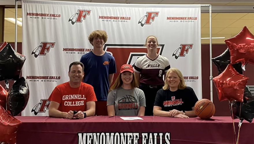 Sara sits at a table with her parents as a high school senior at her signing celebration to play for Grinnell