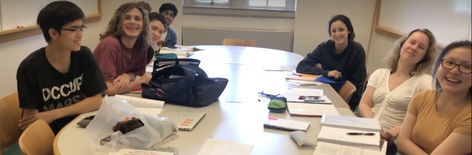 Students surround a table in a classroom