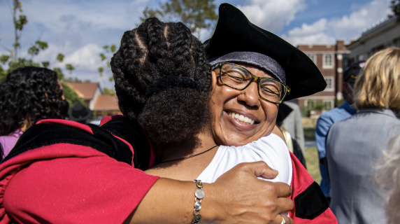 Two people in graduation attire embrace